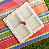 White divided dish on a colorful striped fabric with grass underneath