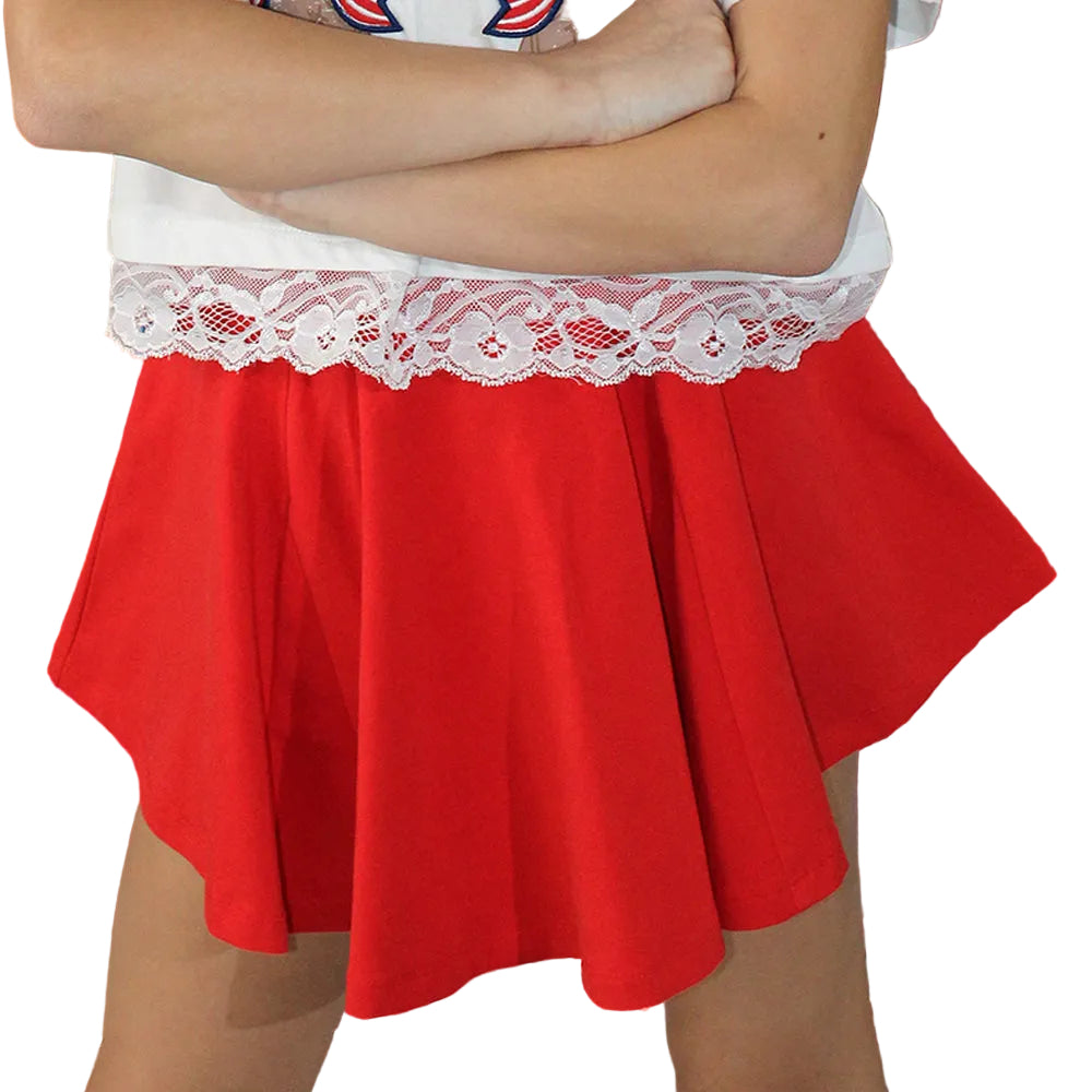 Red skirt with white lace top worn by a person against a festive background