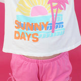 White crop top with 'Sunny Days' text and palm tree design on a pink background