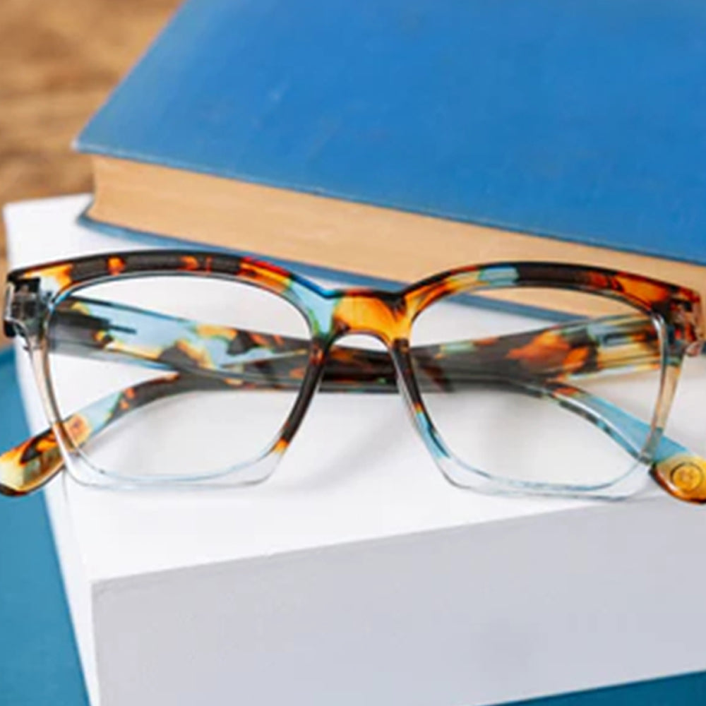 Tortoiseshell glasses on a stack of books with a blurred background