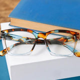 Tortoiseshell glasses on a stack of books with a blurred background