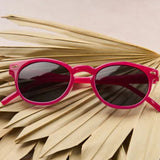 Pink sunglasses on a dried palm leaf