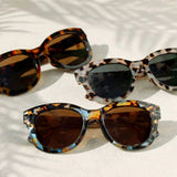 Three pairs of tortoiseshell sunglasses on a light background