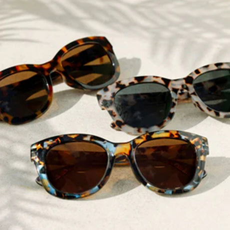 Three pairs of tortoiseshell sunglasses on a light background