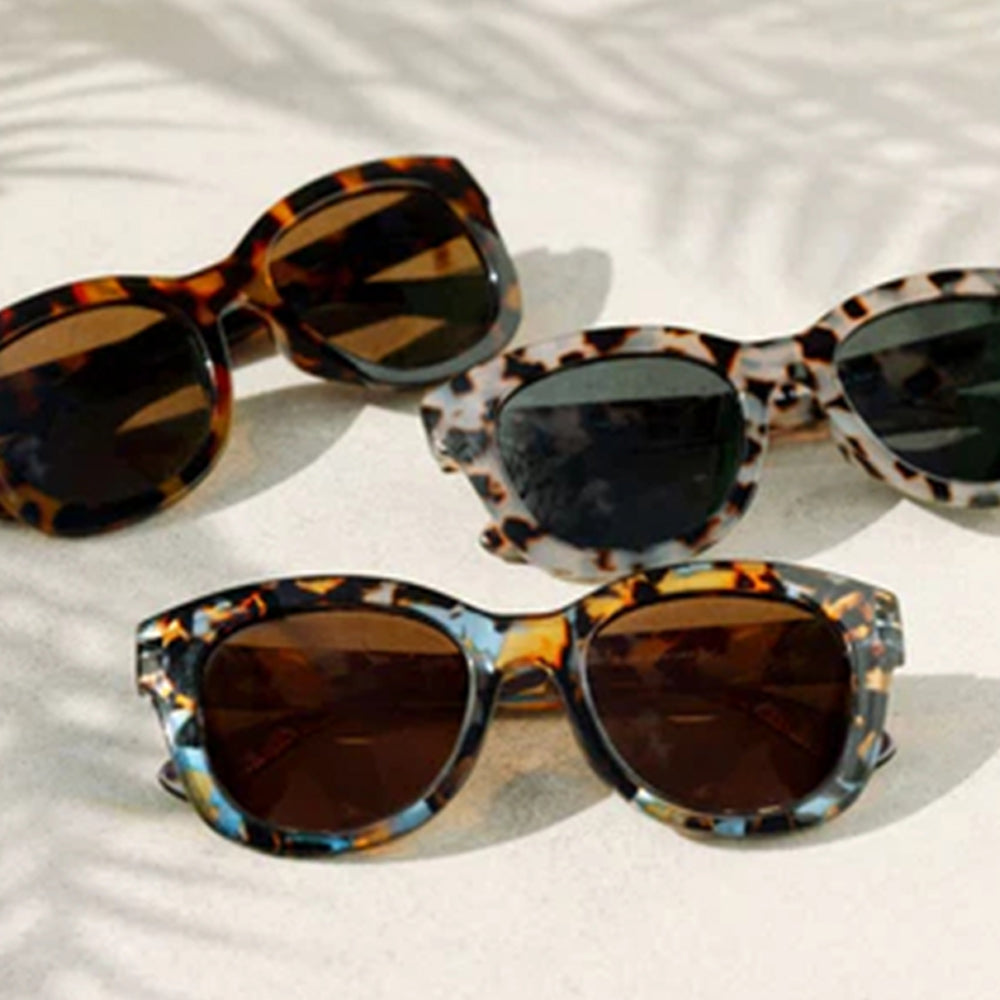 Three pairs of tortoiseshell sunglasses on a light background