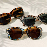 Three pairs of tortoiseshell sunglasses on a light background
