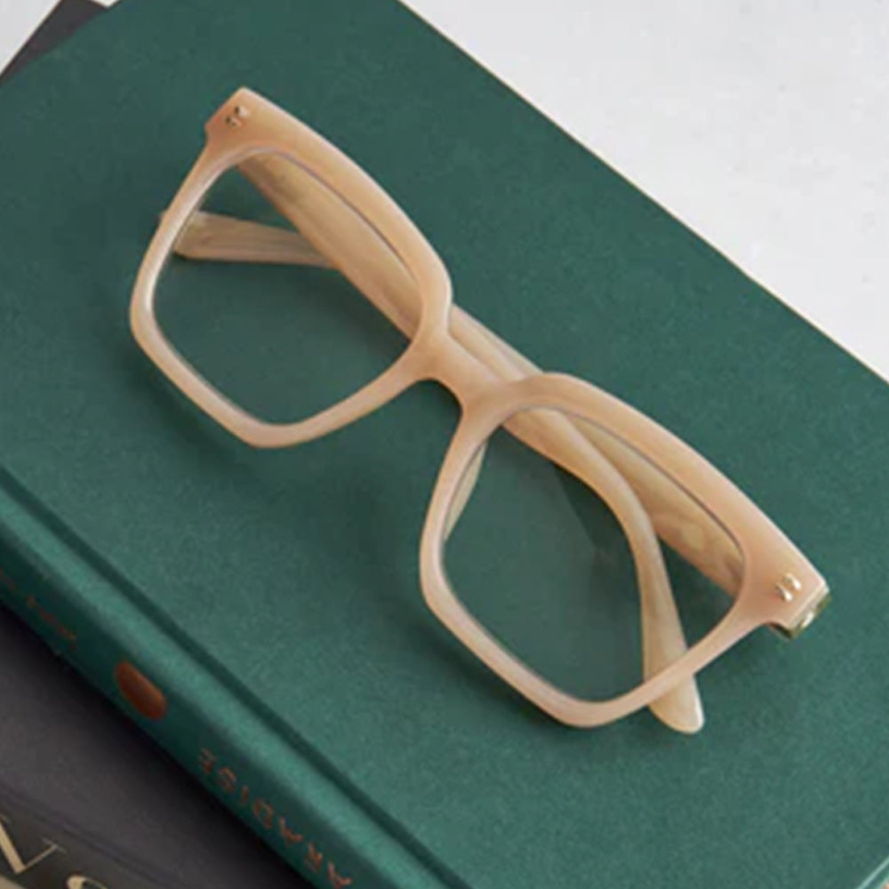 Beige eyeglasses on a green book
