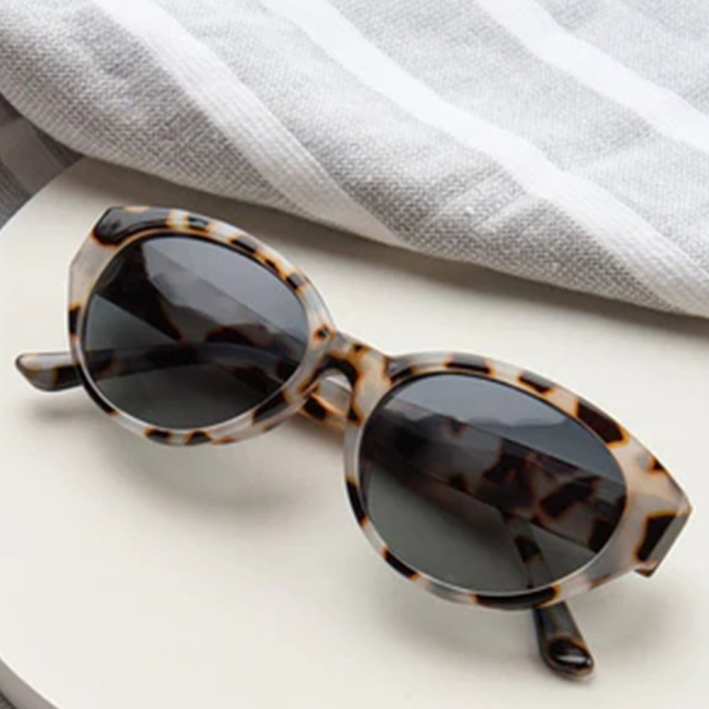 Sunglasses with tortoiseshell frame and dark lenses on a light background