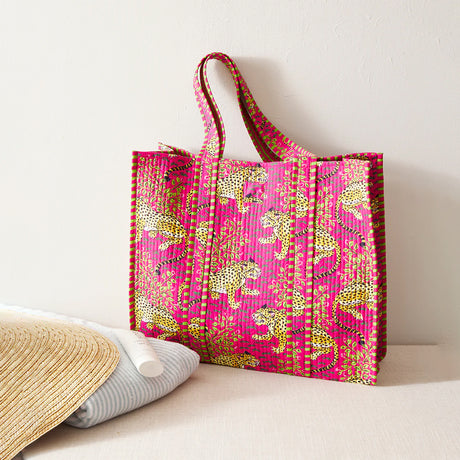 Pink tote bag with yellow patterns on a white surface