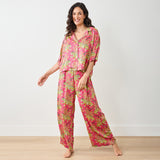 Woman wearing a pink patterned pajama set on a plain background