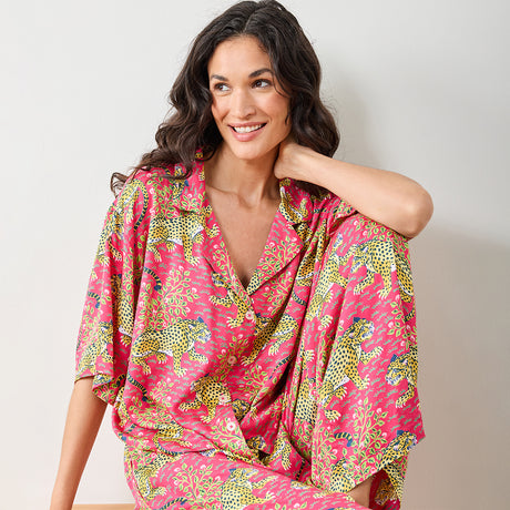 Woman wearing a pink patterned outfit with leopards on a plain background