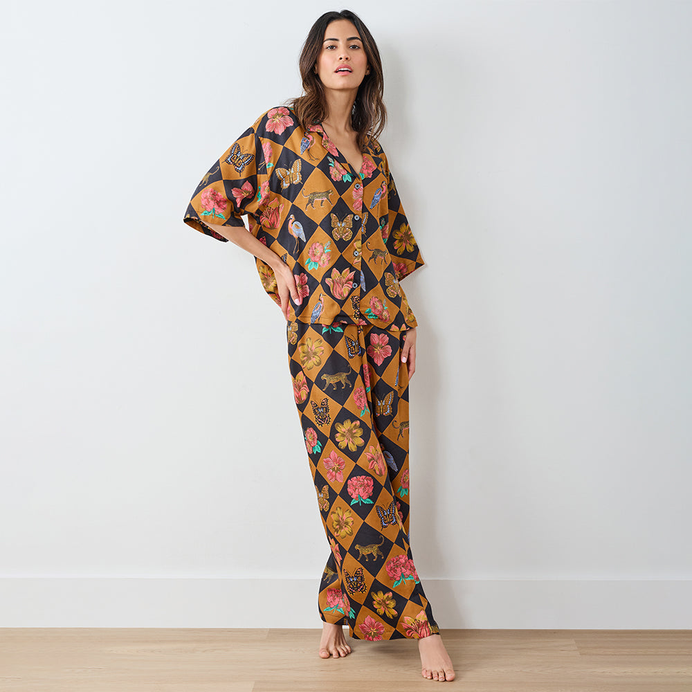 Woman wearing a colorful patterned pajama set against a white wall.