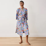 Person wearing a colorful robe with a pattern on a plain background