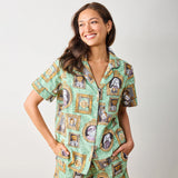 Woman wearing a green patterned shirt with portrait designs on a plain background