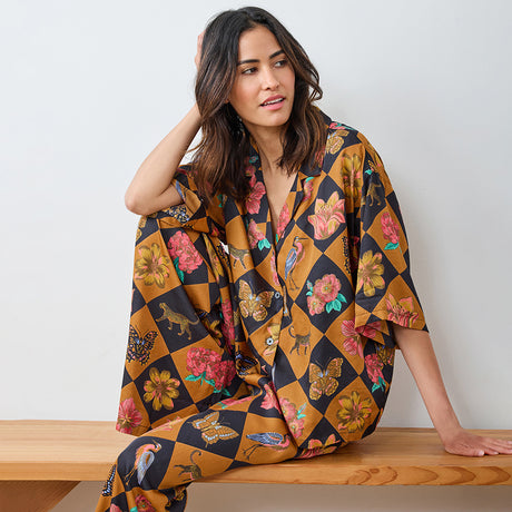 Woman wearing a colorful patterned kimono-style garment sitting on a wooden bench.
