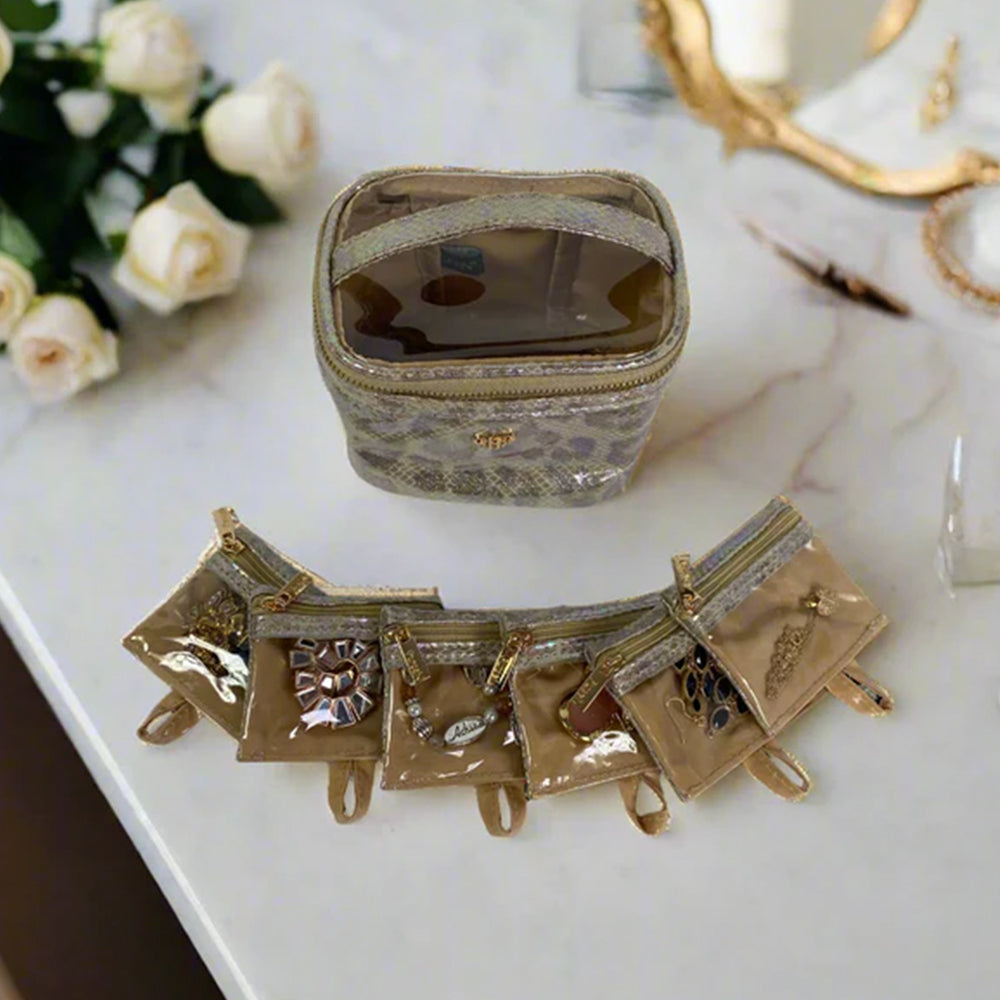 Gold jewelry set on a marble surface with flowers in the background