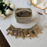 Gold jewelry set on a marble surface with flowers in the background