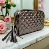 Quilted makeup bag with tassel on a marble surface with flowers in the background