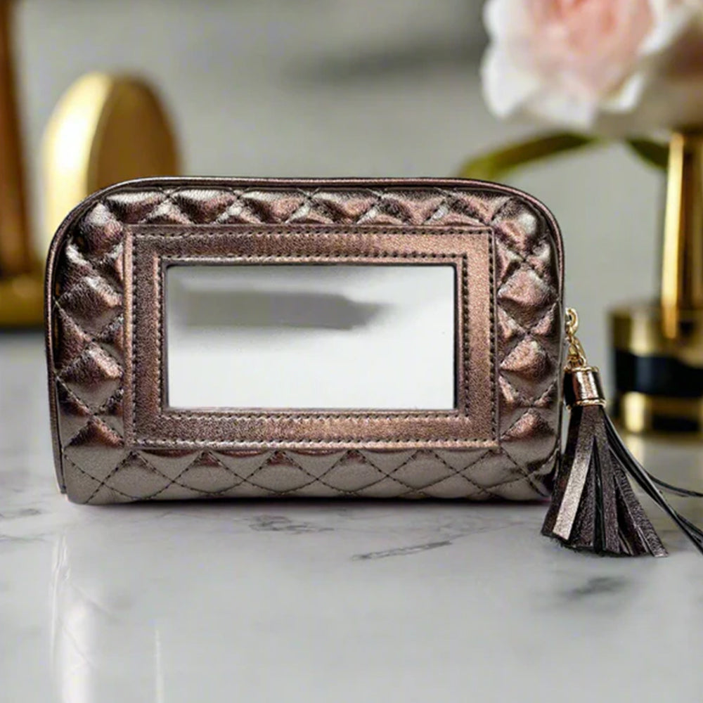Rose gold makeup bag with mirror and tassel on a marble surface