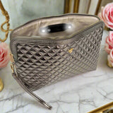 Quilted makeup bag on a marble surface with flowers in the background