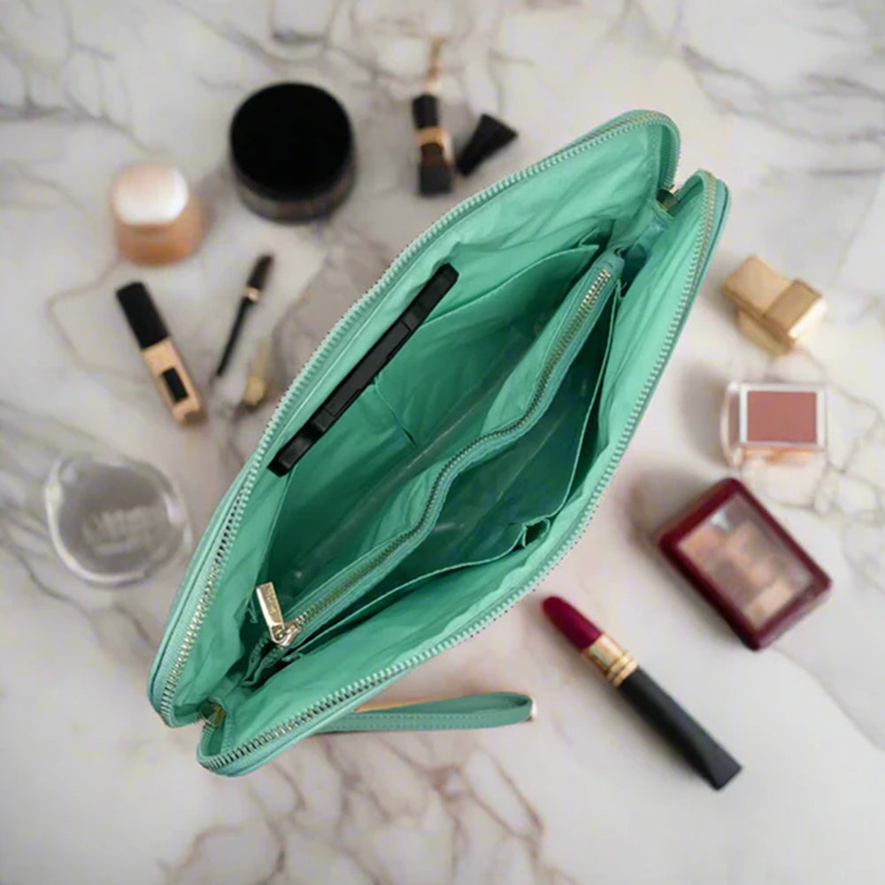 Open teal makeup bag with various cosmetics on a marble surface