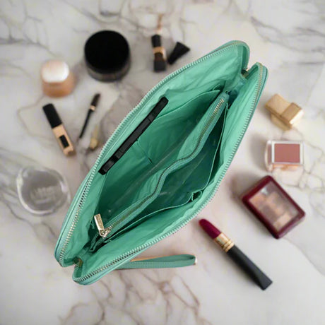 Open teal makeup bag with various cosmetics on a marble surface