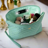 Mint green makeup bag with cosmetic items on a marble surface