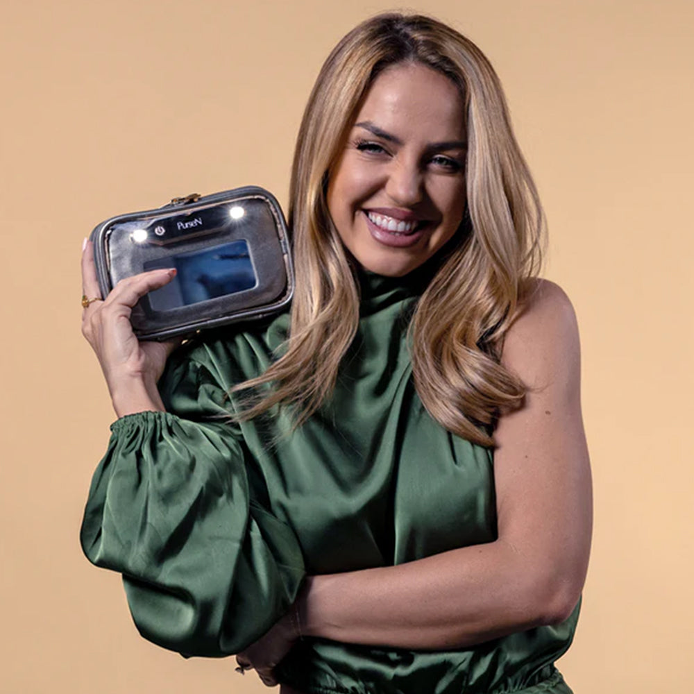 Woman holding a small black device with a screen against a beige background