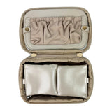 Open beige jewelry case with silver jewelry inside on a white background