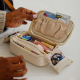 Open beige jewelry box with various items on a white surface