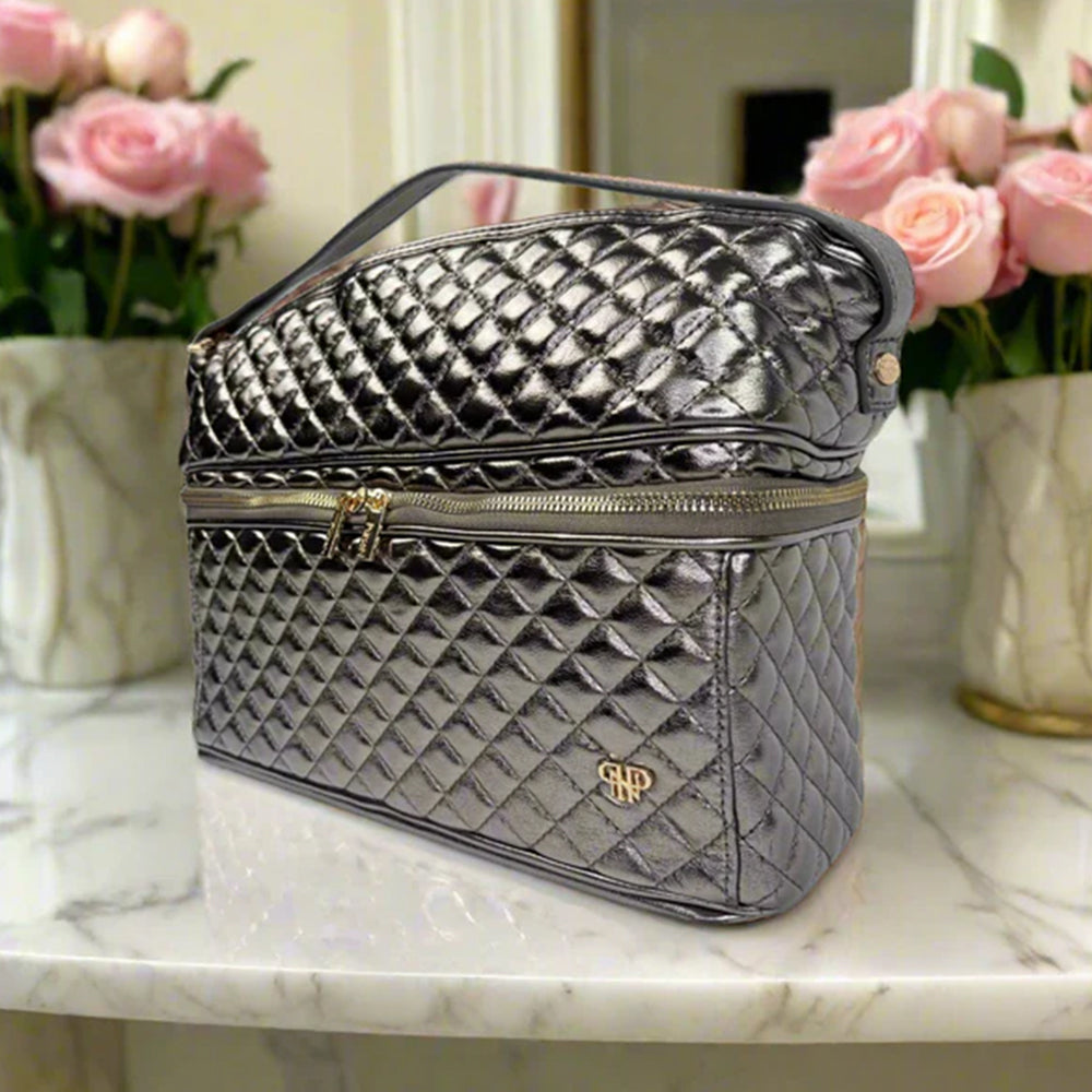 Quilted gray cosmetic bag on a marble surface with pink flowers in the background