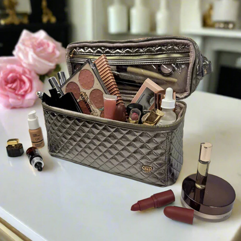 Quilted makeup bag with cosmetic items on a table with flowers in the background