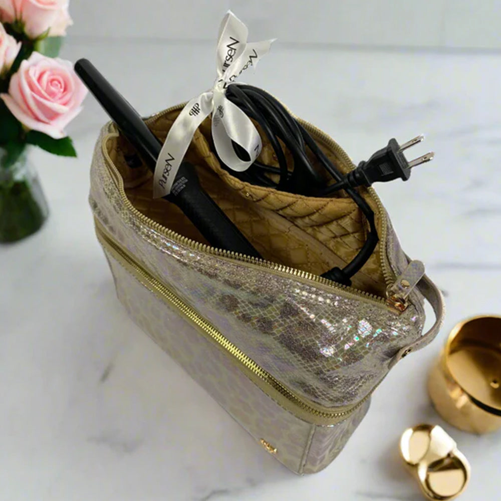Gold glittery pouch with electronic accessories on a light surface with flowers in the background