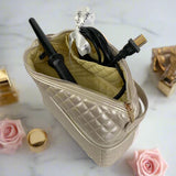 Quilted beige travel bag with hair straightener and cable on a marble surface with roses.