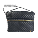 Black quilted makeup bag with gold zipper and heat resistant top compartment label on a white background
