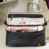 Black quilted makeup bag with cosmetic items on a bathroom counter