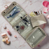 Gold travel pouch with cosmetic items on a marble surface