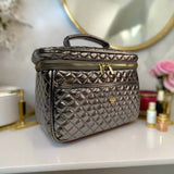 Quilted makeup bag on a vanity with decorative items in the background