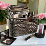 Quilted makeup bag with cosmetic items on a marble surface with flowers in the background