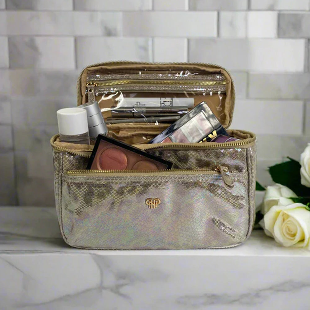 Gold cosmetic bag with makeup items on a marble surface