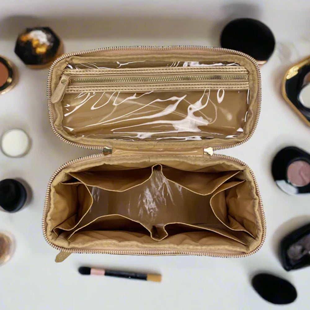 Empty beige makeup case with a clear top compartment on a white background with makeup items.