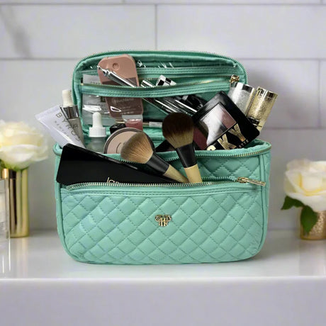 Mint green makeup bag with cosmetic items on a white surface