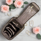 Jewelry case with compartments on a marble surface with pink roses and jewelry.
