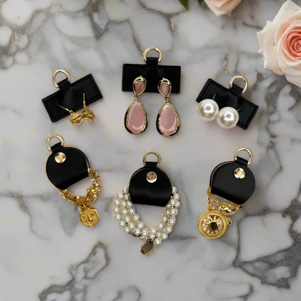 Set of black and gold earrings on a marble surface with flowers in the background