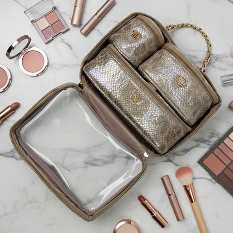 Gold makeup bag with cosmetic items on a marble surface
