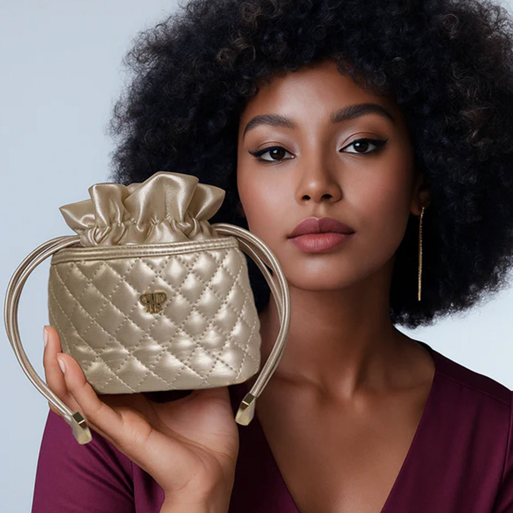 Woman holding a gold quilted handbag against a light blue background