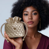 Woman holding a gold quilted handbag against a light blue background