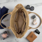 Open beige handbag with makeup items on a marble surface