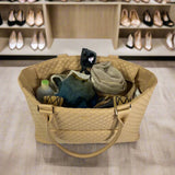 Beige quilted handbag with contents on a light surface, with shoes in the background