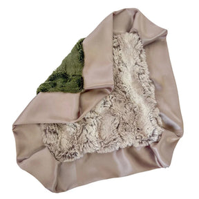 A folded throw blanket featuring a smooth taupe satin-like exterior, a plush cream sherpa-like interior, and a folded green fabric section on one side, shown against a plain white background.
